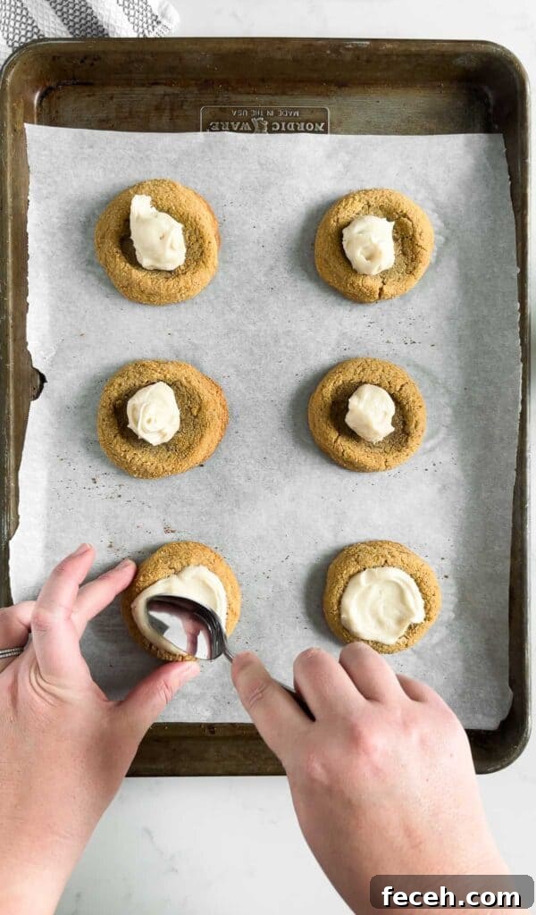 spreading cheesecake filling onto strawberry cheesecake cookies