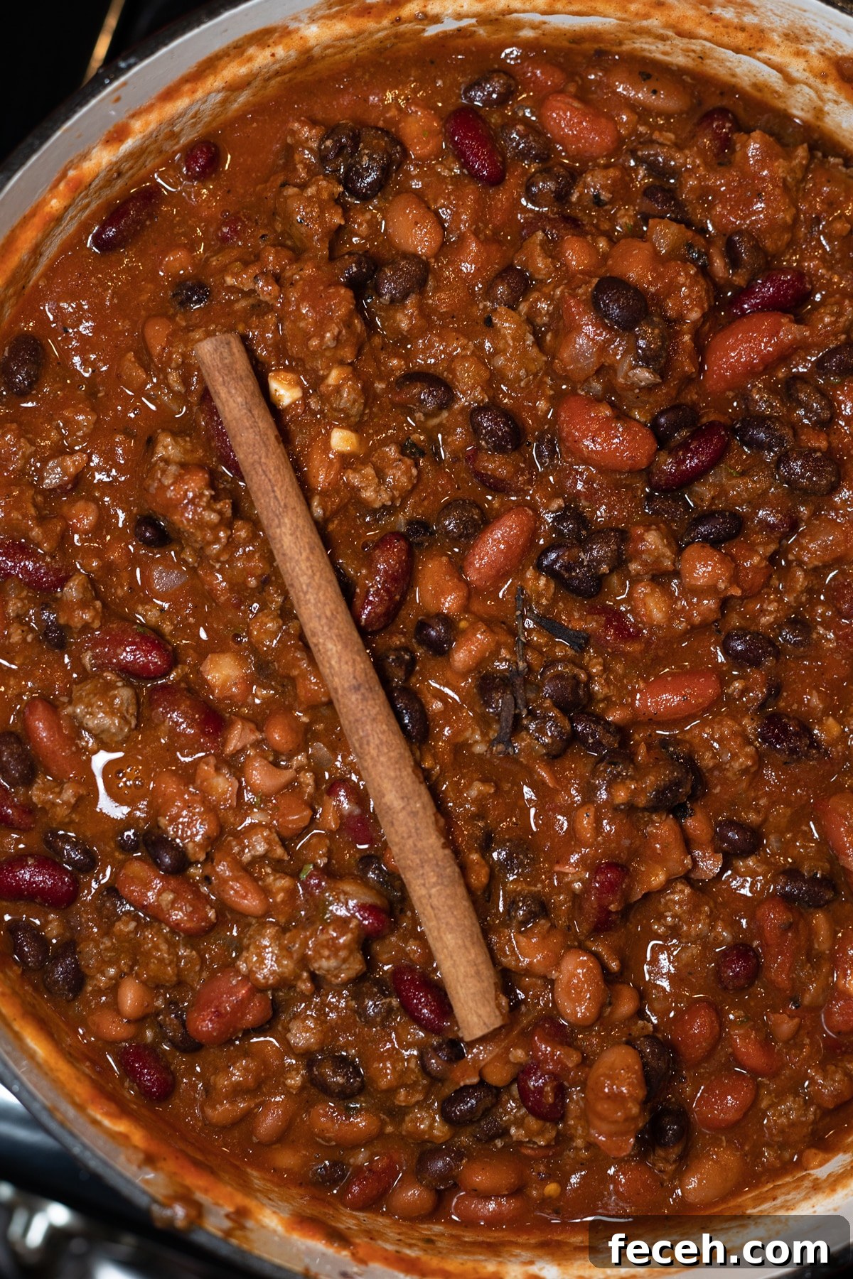 Hearty Three-Bean Chili Recipe: Simple Weeknight Dinner 11 Large pot of chili on the stove with stick of cinnamon.