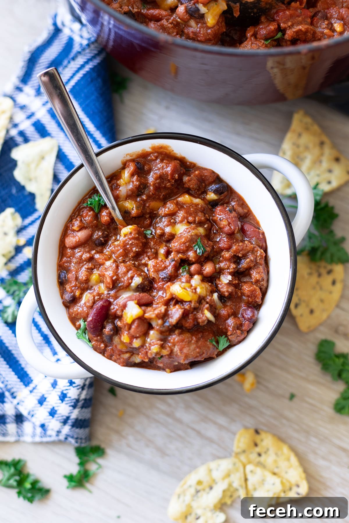 Hearty Three-Bean Chili Recipe: Simple Weeknight Dinner 12 Spoon in a bowl of chili, chips on table.