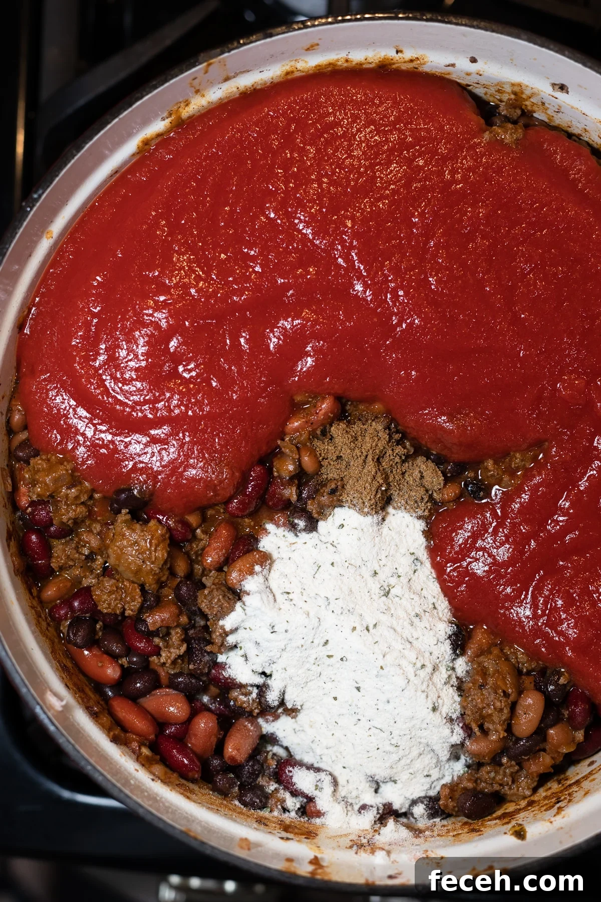 Hearty Three-Bean Chili Recipe: Simple Weeknight Dinner 10 Chili sauce, beans, ground beef, and other ingredients in a large pot.