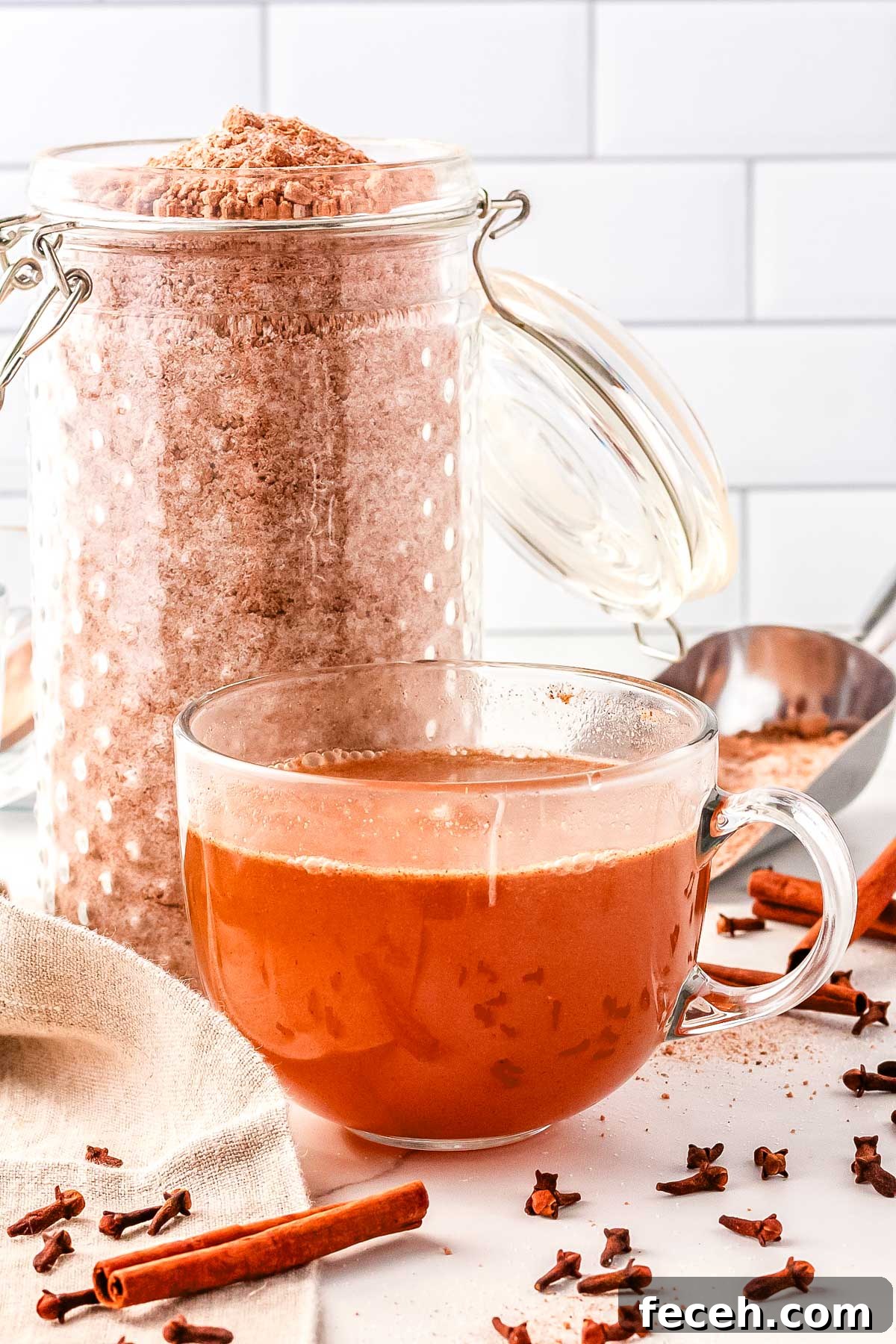 A jar of apple cider mix and then a teacup with spiced apple cider in it made with the mix.
