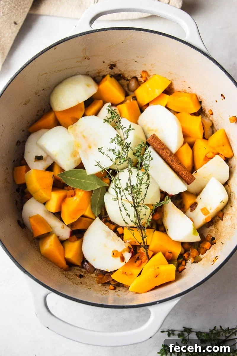 Creamy Butternut Squash and Apple Soup Recipe for Fall 6 Apples, cinnamon stick, butternut squash and fresh thyme added to the pot, fresh thyme, and a dish towel.