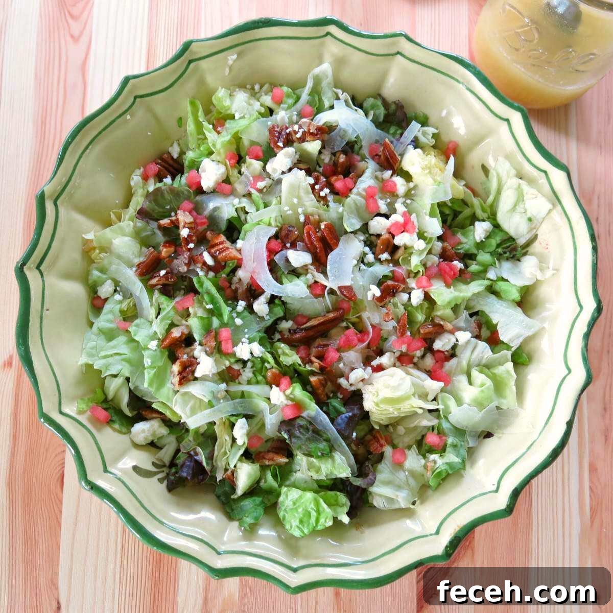 Summer Fennel Salad with Feta, Watermelon and Toasted Pecans 2 Bowl of summer salad with fennel, watermelon, feta, and candied pecans with a jar of Orange honey mustard vinaigrette in a mason jar behind it.