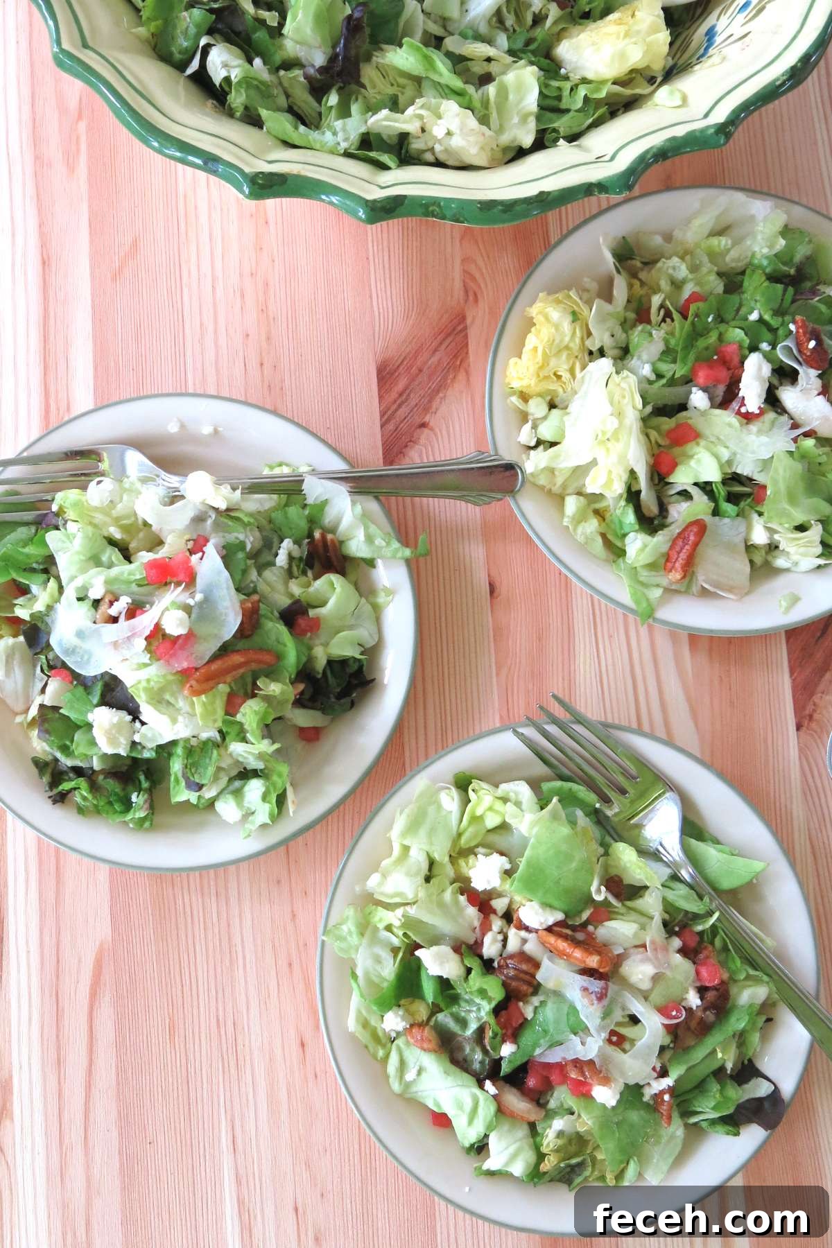 Summer Fennel Salad with Feta, Watermelon and Toasted Pecans 11 Three small side salads of the fancy salad with shaved fennel, candied pecans, watermelon, and feta cheese on plates with the bowl behind it.