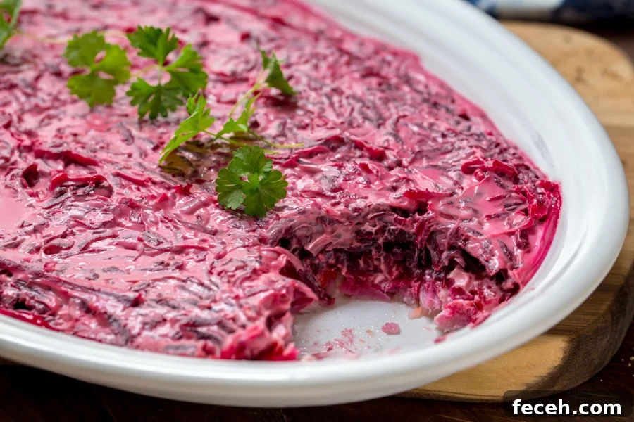 Russian and Ukrainian Shuba Salad layered on a white oval plate with herring fish, potatoes, carrots, beets , and mayo