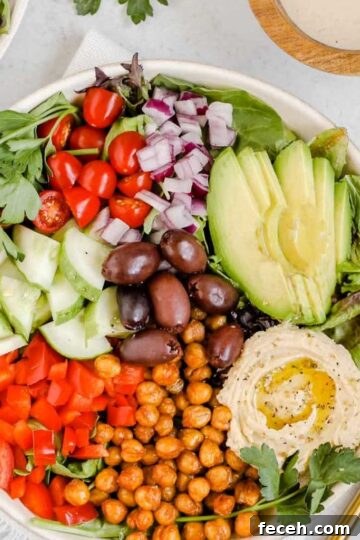 Mediterranean salad in shallow salad bowl with side of tahini dressing.