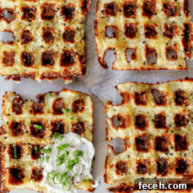 Ultimate Keto Chaffle Recipes: Savory & Sweet Ways to Use Chaffles 11 Sliced keto chaffles topped with melted cheese and bacon bits, served with a dollop of sour cream and garnished with chopped green onions.