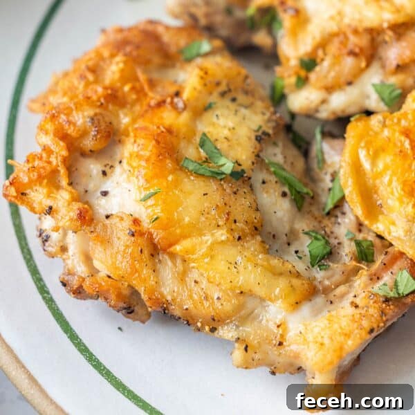 Ultimate Keto Chaffle Recipes: Savory & Sweet Ways to Use Chaffles 6 Close-up of pan fried chicken thighs with crispy golden skin, seasoned with black pepper and garnished with chopped fresh herbs on a white plate—a delicious keto fried chicken recipe.