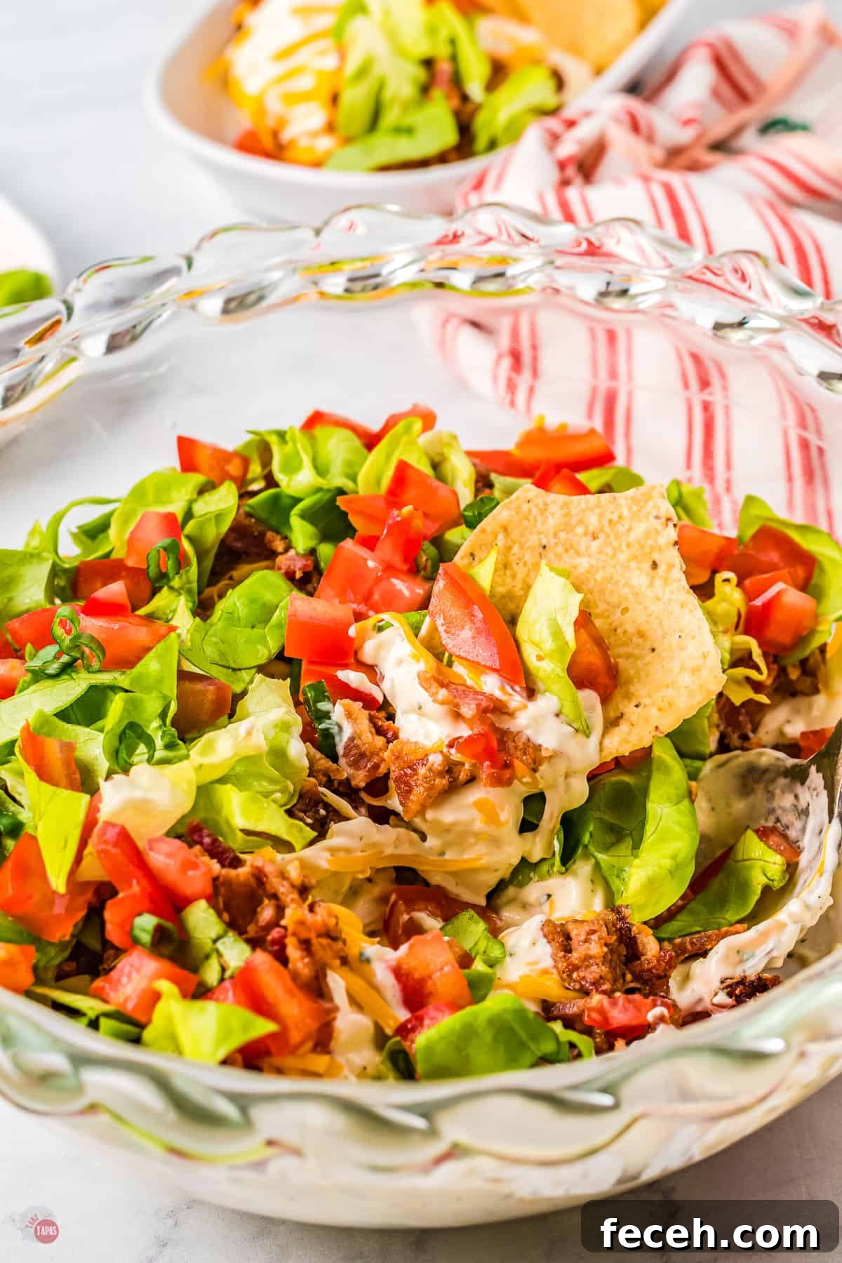 Glass bowl of BLT Dip with chips in it.
