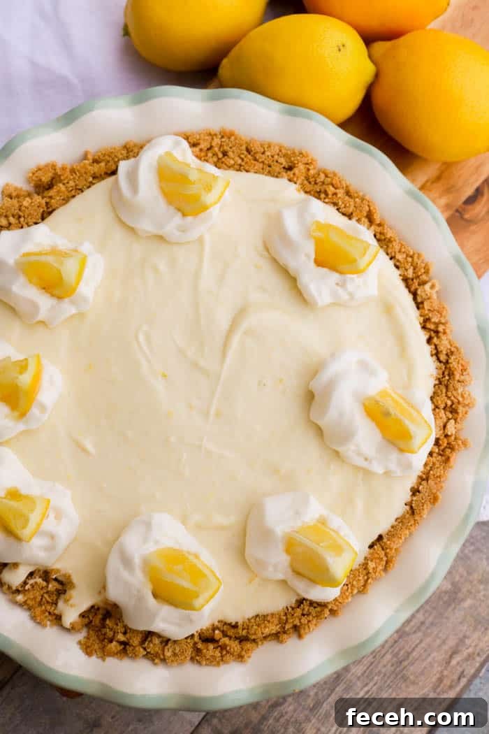 No-Bake Lemon Cream Pie Recipe: Light, Zesty, No-Oven Dessert 4 top view picture of No Bake Lemon Pie in a white pie pan topped with lemon slices