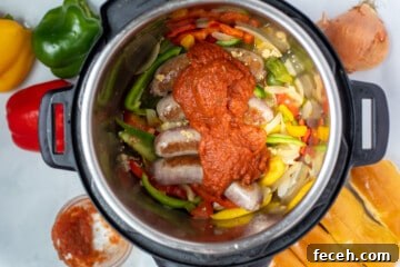 Sausage, peppers, onions, and tomato sauce layered in instant pot.