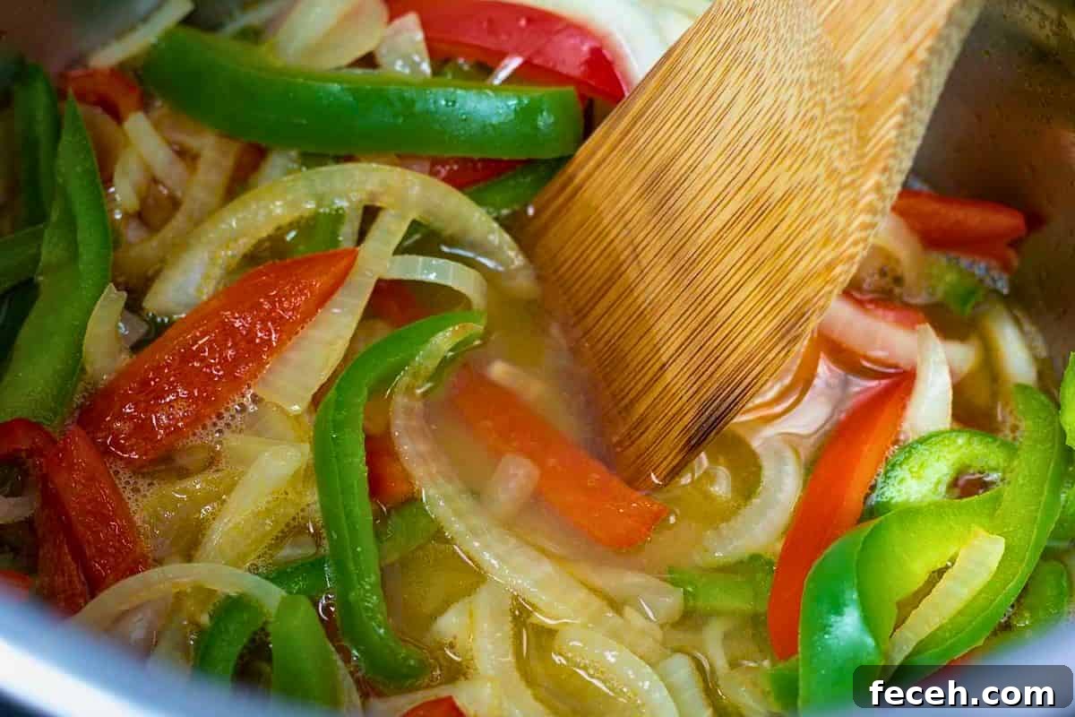 Wooden spoon deglazing inner pot after sauteing peppers and onions in inner pot.