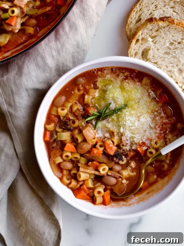 A bowl of traditional Italian pasta fagioli soup in a bowl with spoon and side of bread.