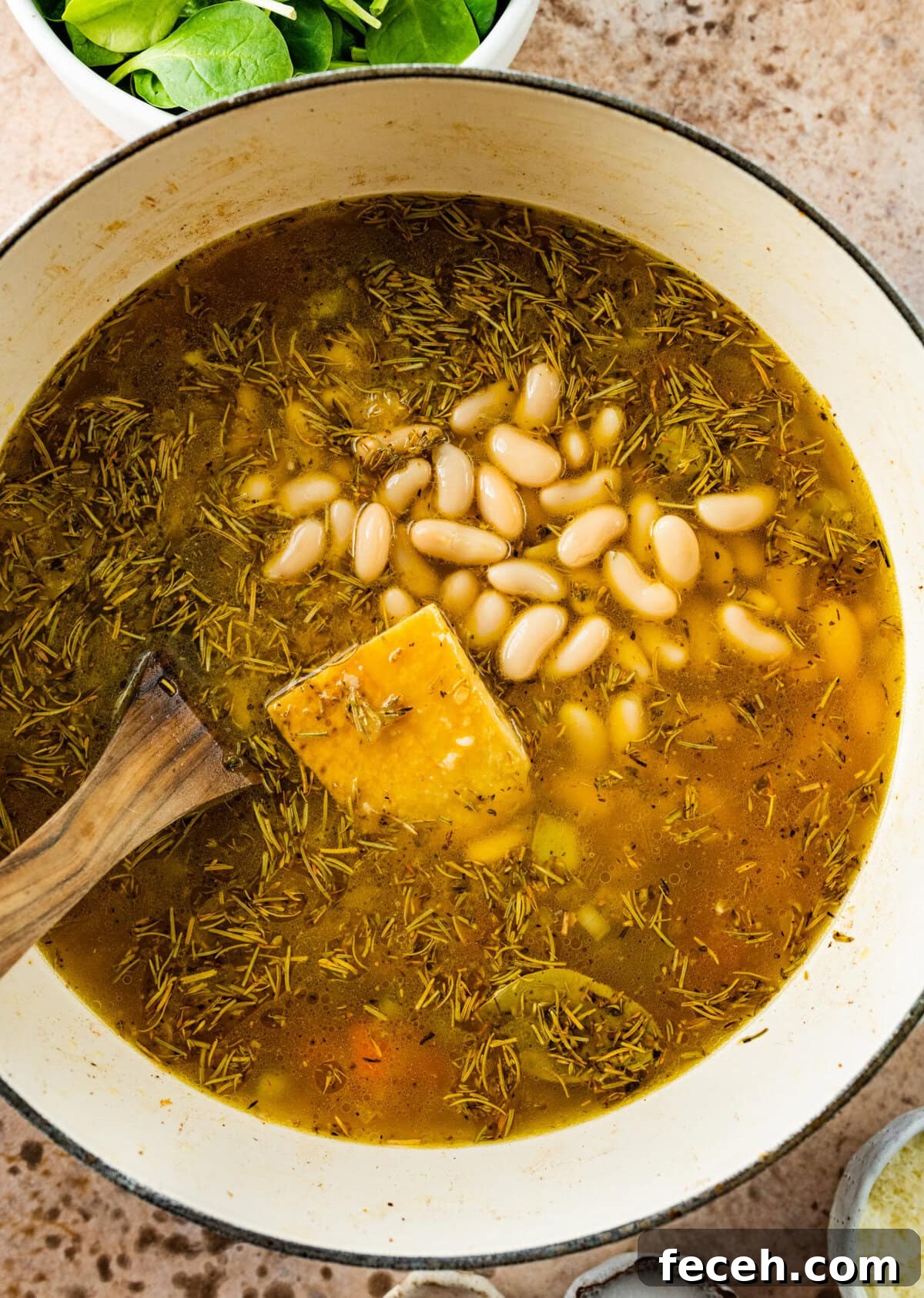 add the beans and parmigiano rind to the large soup pot and cook.