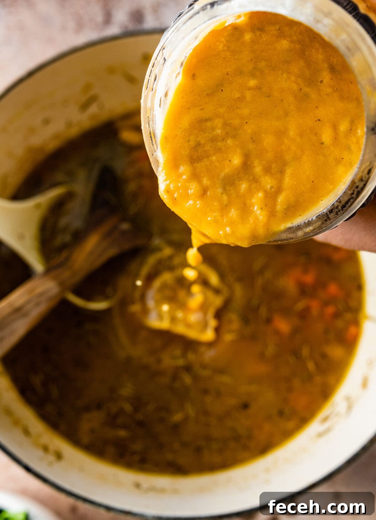blended portion of the soup being added back into the pot.