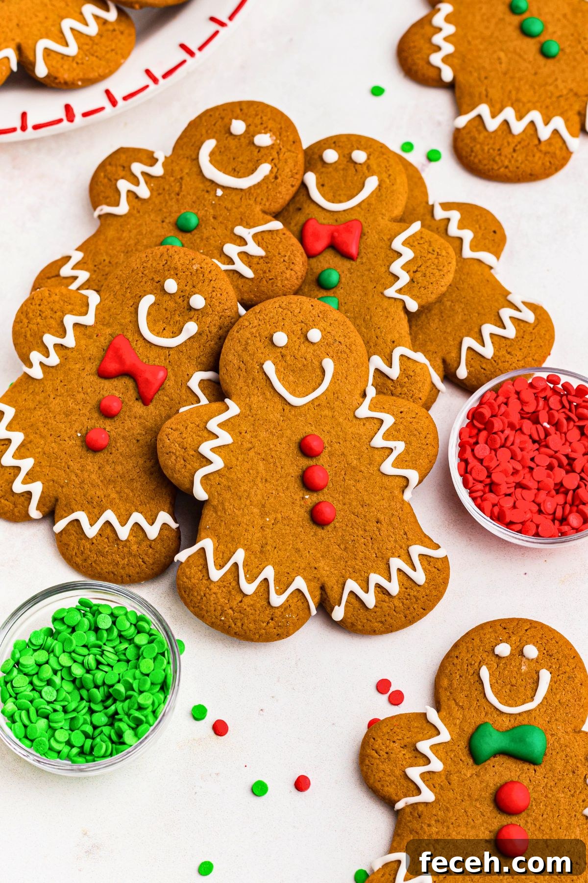 Classic Gingerbread Cookie Recipe for Soft, Spiced Cookies 2 Golden brown gingerbread men cookies stacked on a marble table with holiday sprinkles scattered around the table.