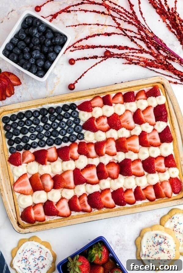 Classic Gingerbread Cookie Recipe for Soft, Spiced Cookies 16 Rectangle cookie in cookie pan, topped with frosting, blueberries and strawberries, on a marble table.