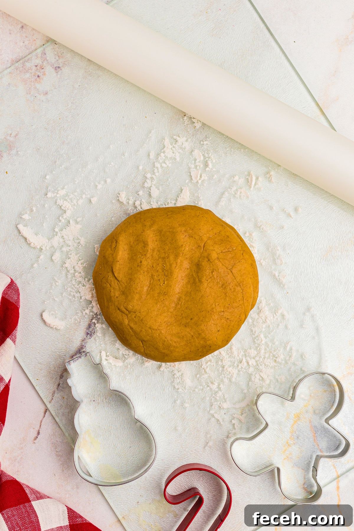 Classic Gingerbread Cookie Recipe for Soft, Spiced Cookies 7 Golden round disc of gingerbread cookie dough, with cookie cutters and rolling pin on marble table.