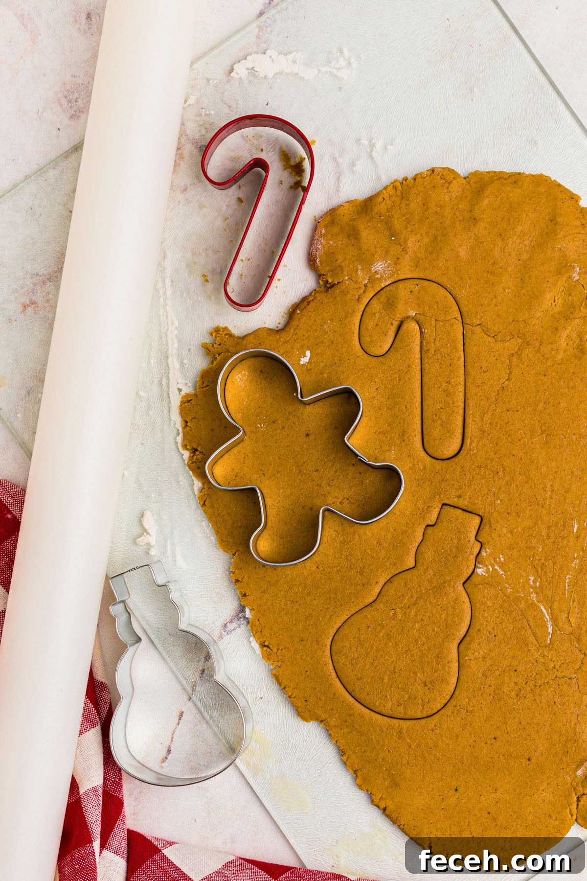 Classic Gingerbread Cookie Recipe for Soft, Spiced Cookies 8 gingerbread cookie dough rolled out and being shaped with cookie cutters.