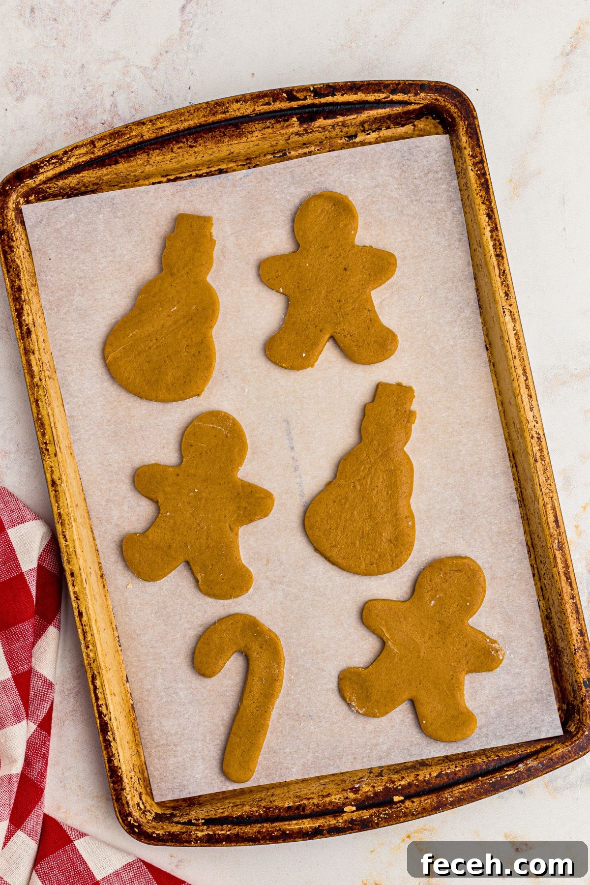 Classic Gingerbread Cookie Recipe for Soft, Spiced Cookies 9 Uncooked gingerbread cookies on a baking sheet lined with parchment paper.