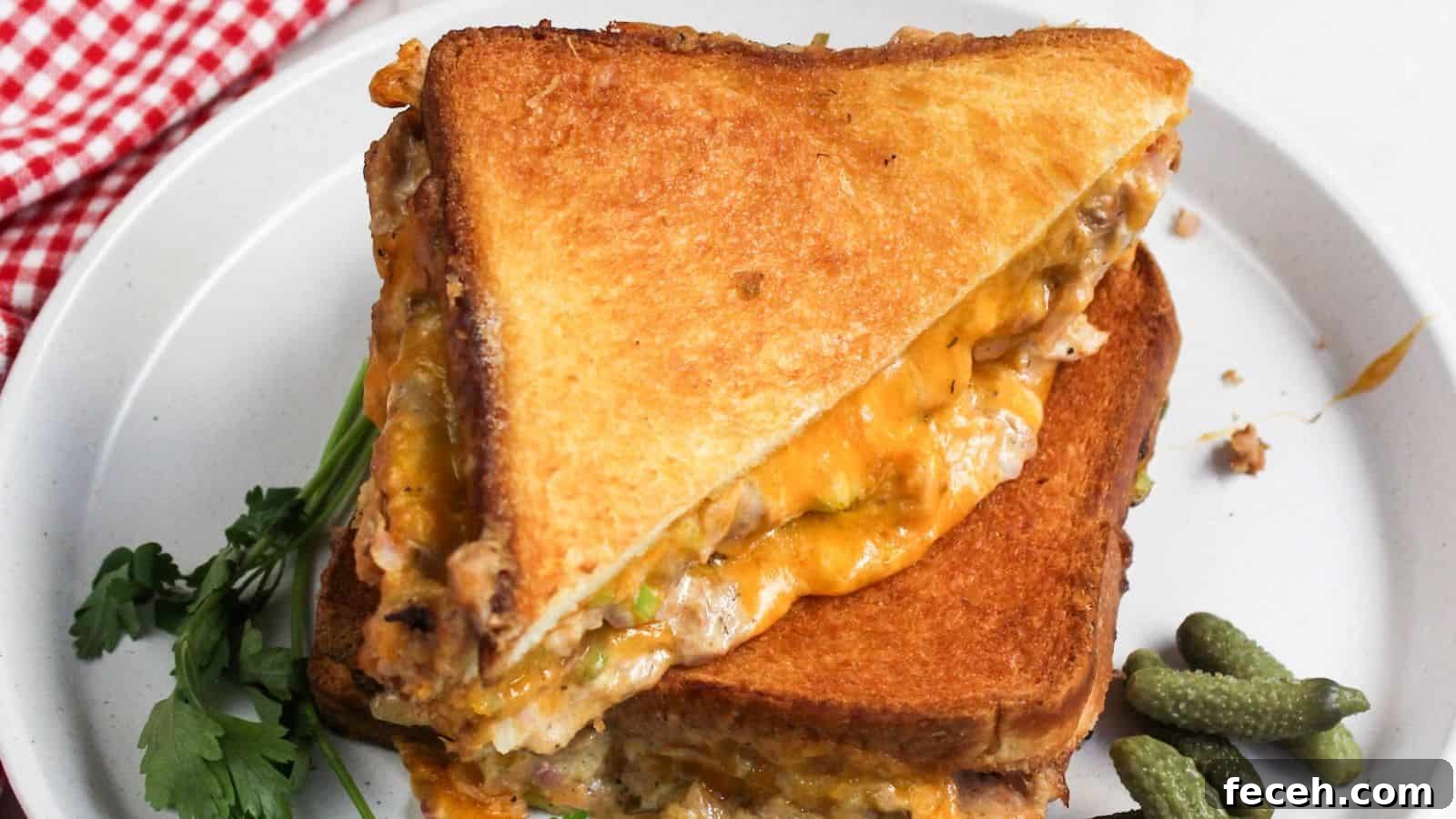 A grilled cheese tuna sandwich is cut in half on a plate.