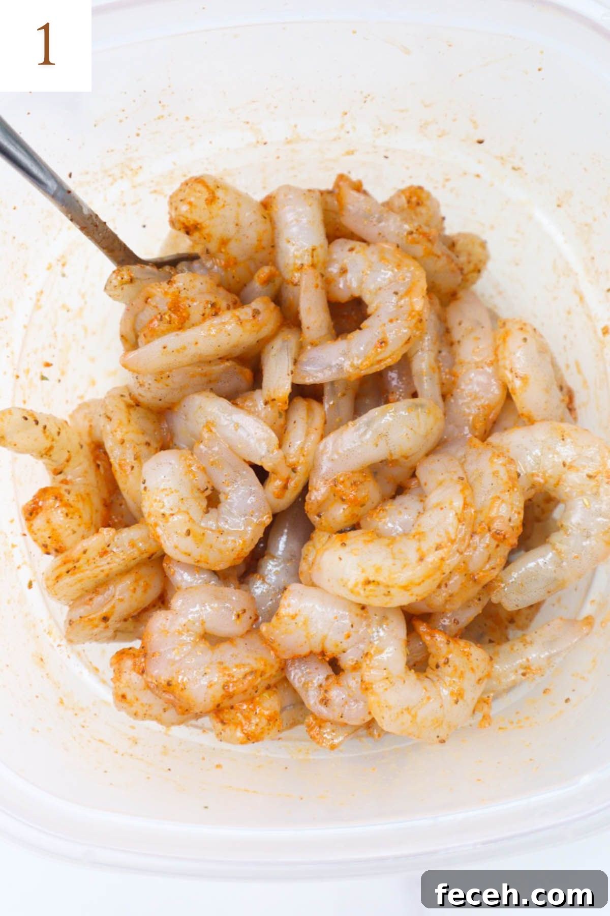 bowl with raw shrimp tossed in old bay seasoning.