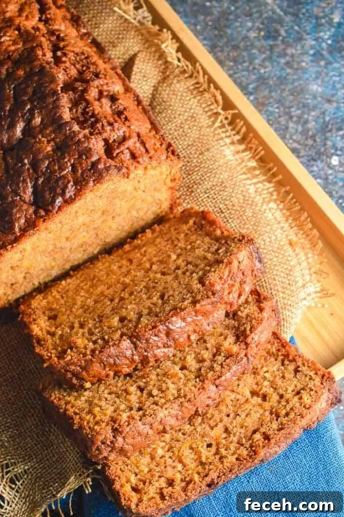 Moist Vegan Pumpkin Bread Recipe for Fall Baking 5 A golden-orange sliced quickbread on a wooden board