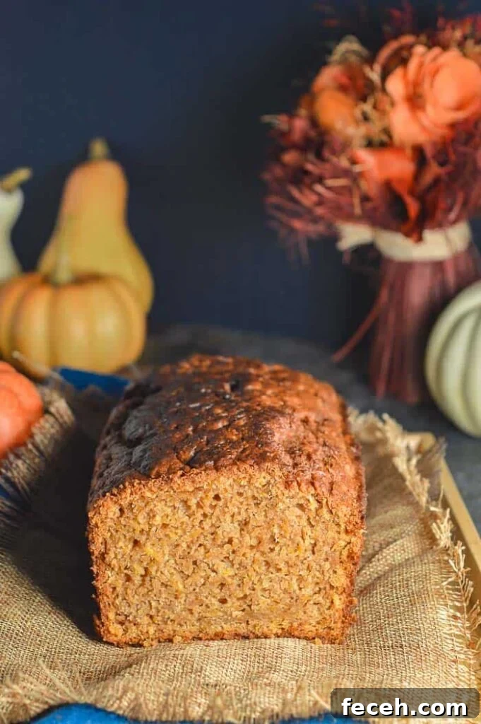 Moist Vegan Pumpkin Bread Recipe for Fall Baking 9 A gold brown quickbread with pumpking and red flowers in the background