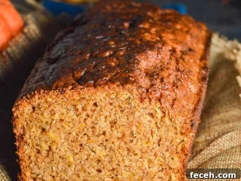 A front cross section view of a golden brown quickbread with pumpkins in the background