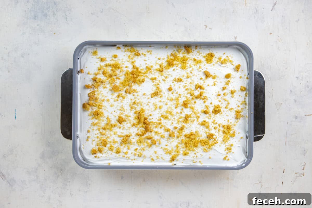 Creamy Lemon Lush Dessert Recipe for Every Occasion 11 Crushed cookies sprinkled on top of the whipped topping in a 9x13-inch baking pan.