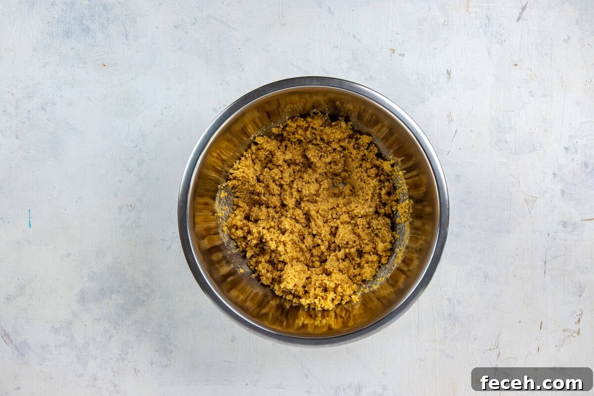 Creamy Lemon Lush Dessert Recipe for Every Occasion 4 Stainless steel mixing bowl with crushed shortbread cookies and melted butter all mixed up.