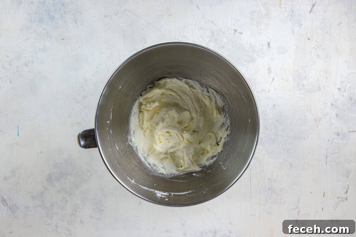 Creamy Lemon Lush Dessert Recipe for Every Occasion 6 Stainless steel mixing bowl with cream cheese, sugar, lemon juice, and 1 cup Cool Whip all mixed up.