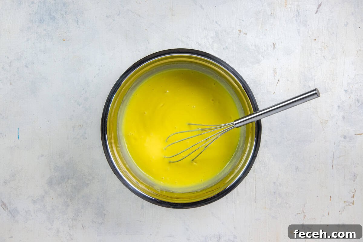 Creamy Lemon Lush Dessert Recipe for Every Occasion 8 Stainless steel mixing bowl with instant lemon pudding mix and milk all mixed up.