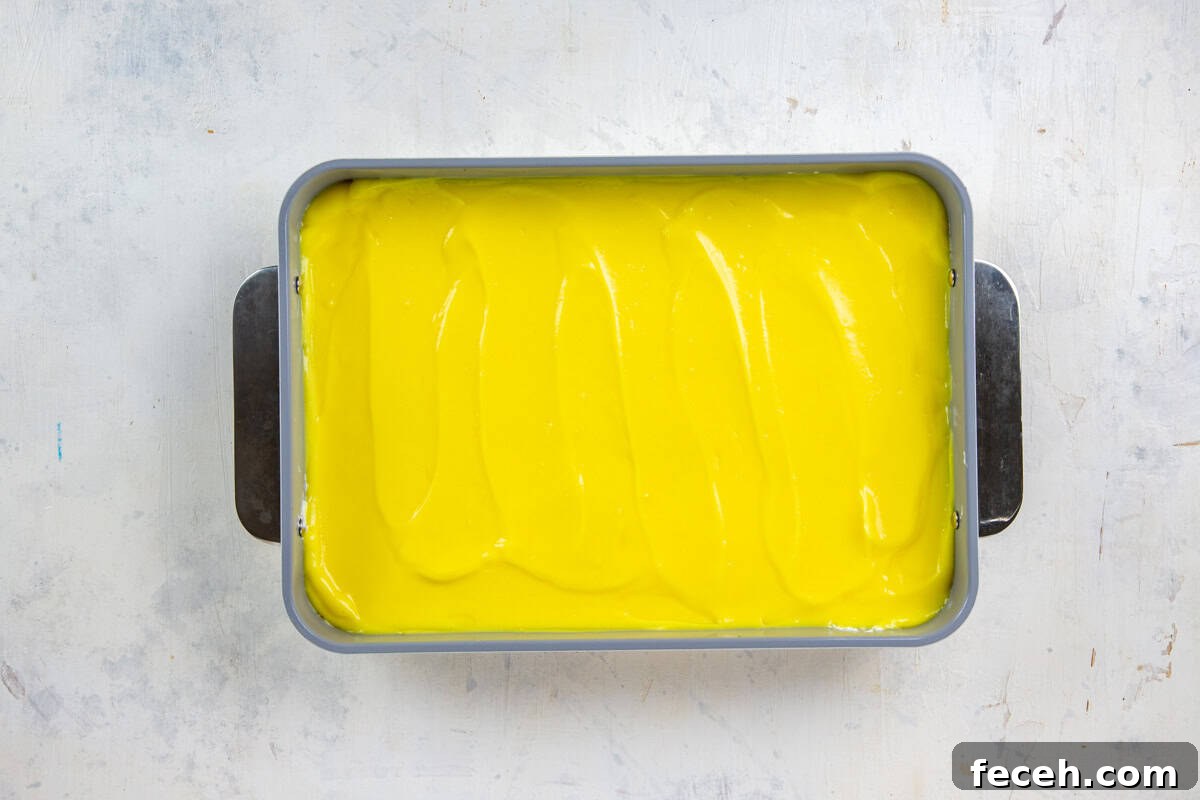Creamy Lemon Lush Dessert Recipe for Every Occasion 9 Lemon pudding spread on top of the cream cheese mixture in a 9x13-inch baking pan.