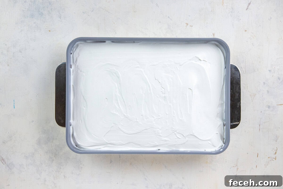 Creamy Lemon Lush Dessert Recipe for Every Occasion 10 Whipped topping spread on top of the pudding layer in a 9x13-inch baking pan.