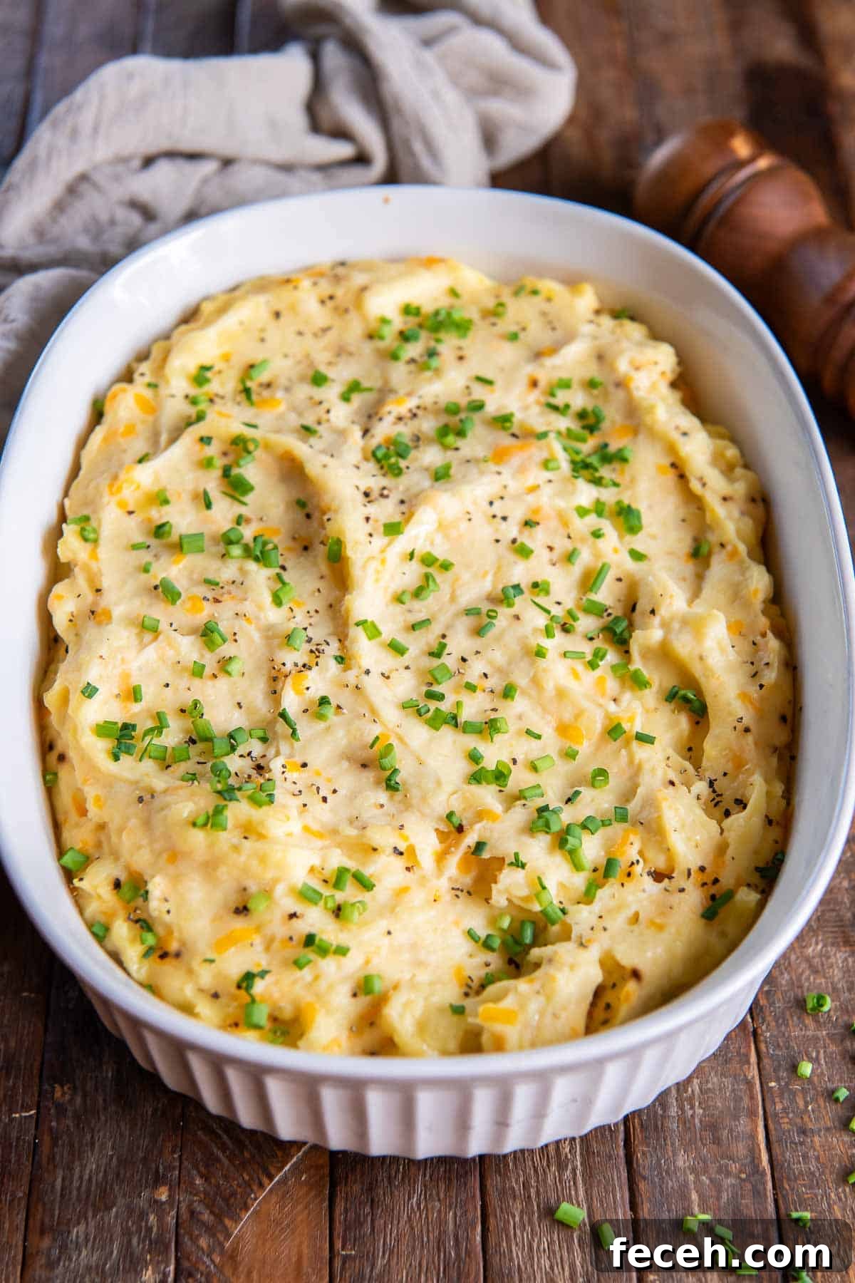 Make-Ahead Mashed Potatoes: Make and Reheat Ahead for Holidays 3 Mashed potatoes in a white baking dish next to a kitchen cloth and pepper shaker.