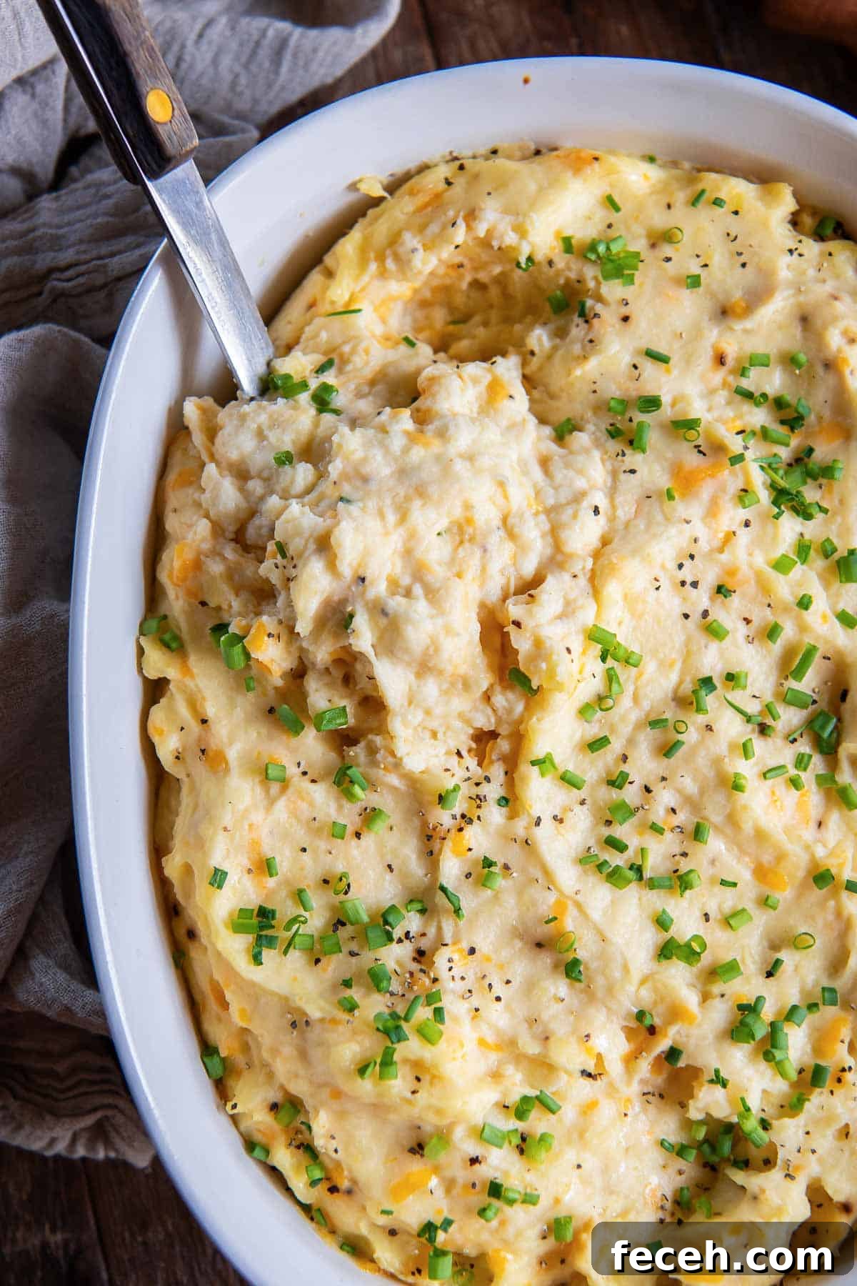 Make-Ahead Mashed Potatoes: Make and Reheat Ahead for Holidays 7 A spoon resting in a baking dish filled with mashed potatoes.
