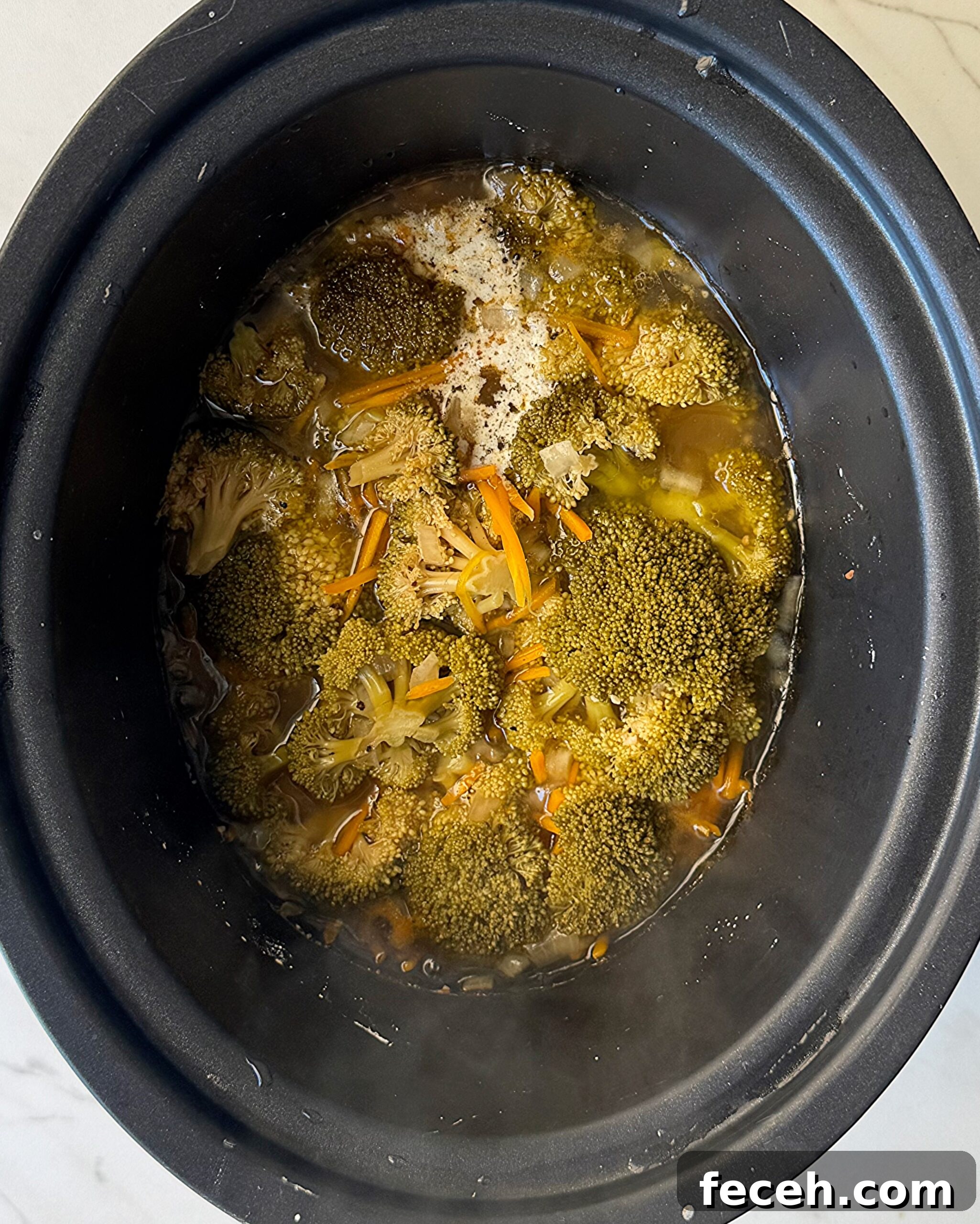 overhead shot of cooked Broccoli Cheddar Soup in a black slow cooker