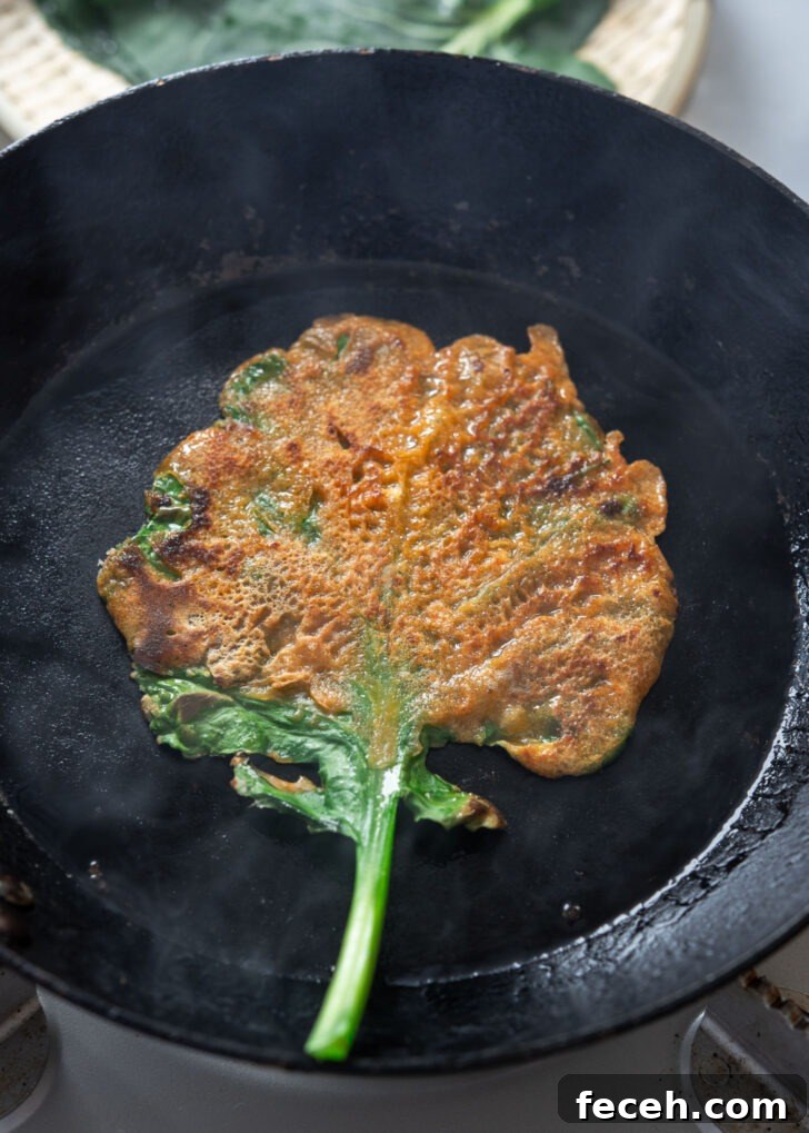 Golden brown kale gochujang pancake (jangtteok) cooked in a skillet