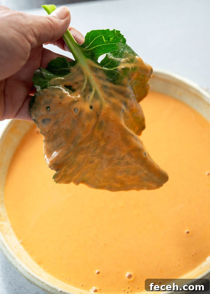 Kale leaf being coated in gochujang pancake (jangtteok) batter