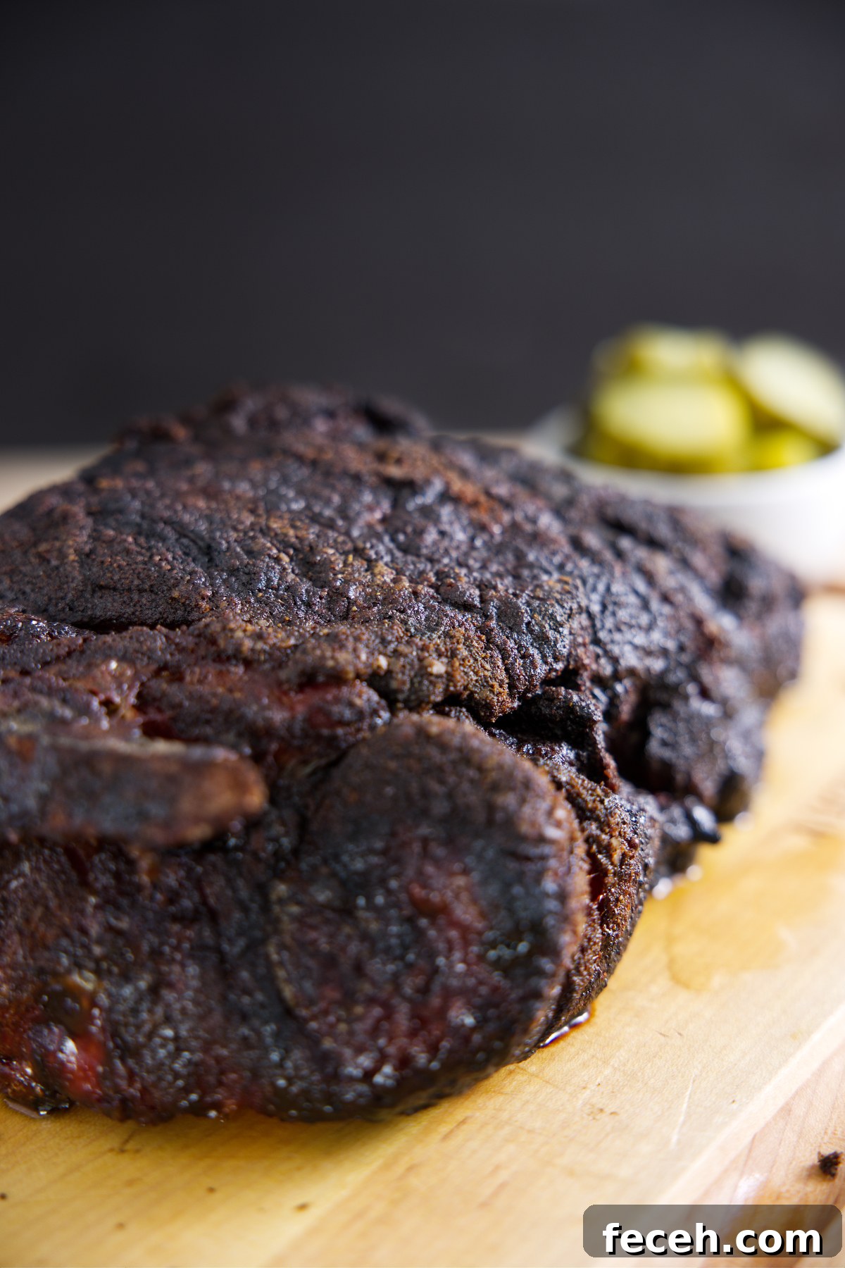 Pork Loin vs Pork Shoulder: Which Cut Should You Cook Tonight? 6 Pork butt resting on cutting board with some pickles in the background.