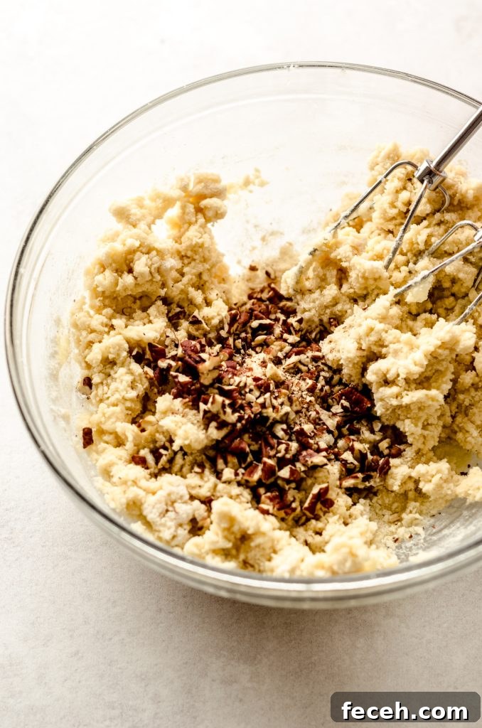 Maple pecan goat cheese sugar cookie dough in a large glass bowl with mixer beaters.