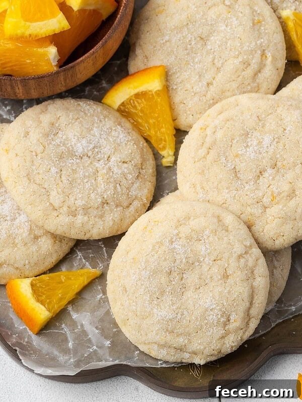 Orange sugar cookies on a parchment paper-lined tray.