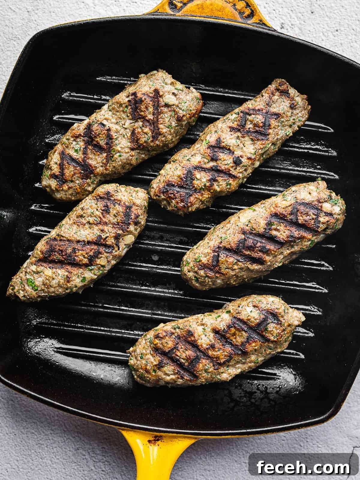 Chicken kafta grilling on a grill pan indoors.