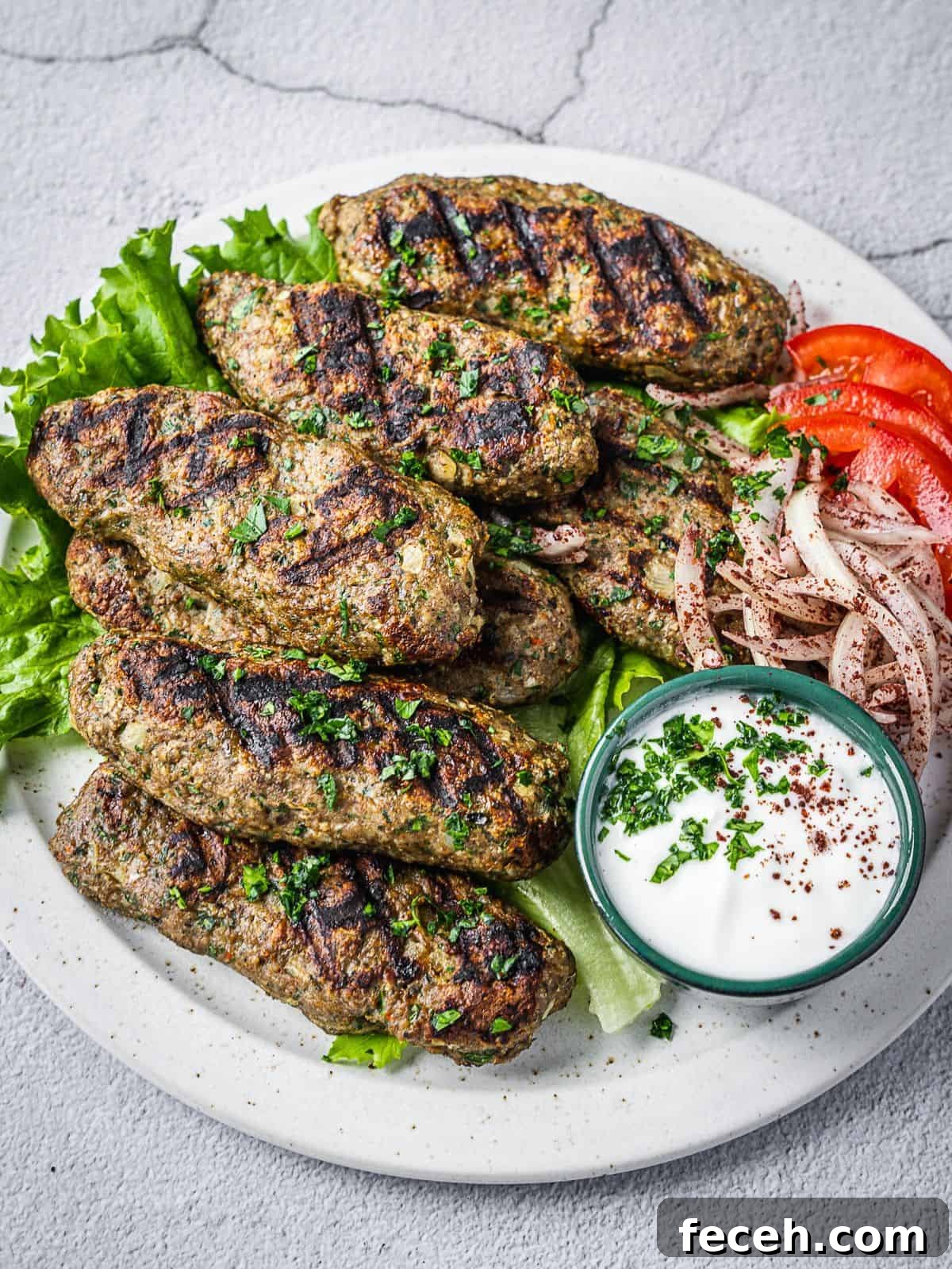 A plate with grilled chicken kafta kebabs with salad and yogurt dipping sauce.