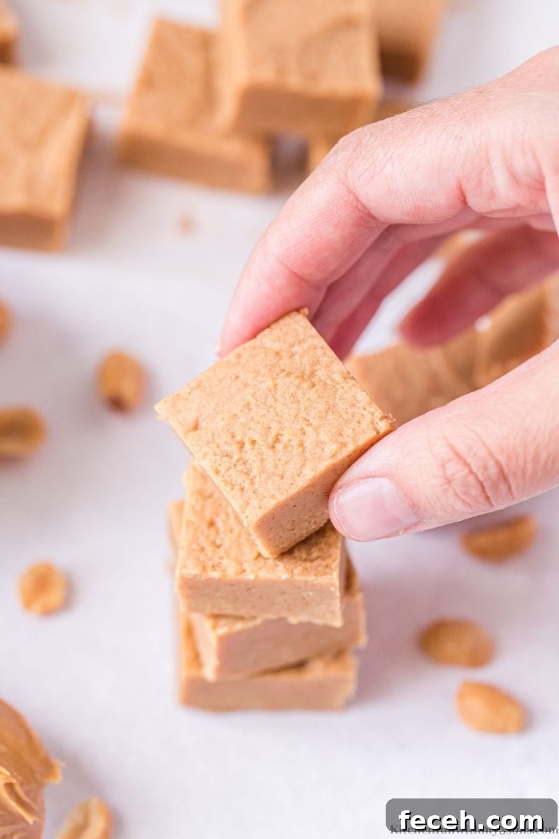 Creamy Peanut Butter Fudge Recipe for Rich, No-Bake Treats 9 A hand holding a piece of the Easy Peanut Butter Fudge.