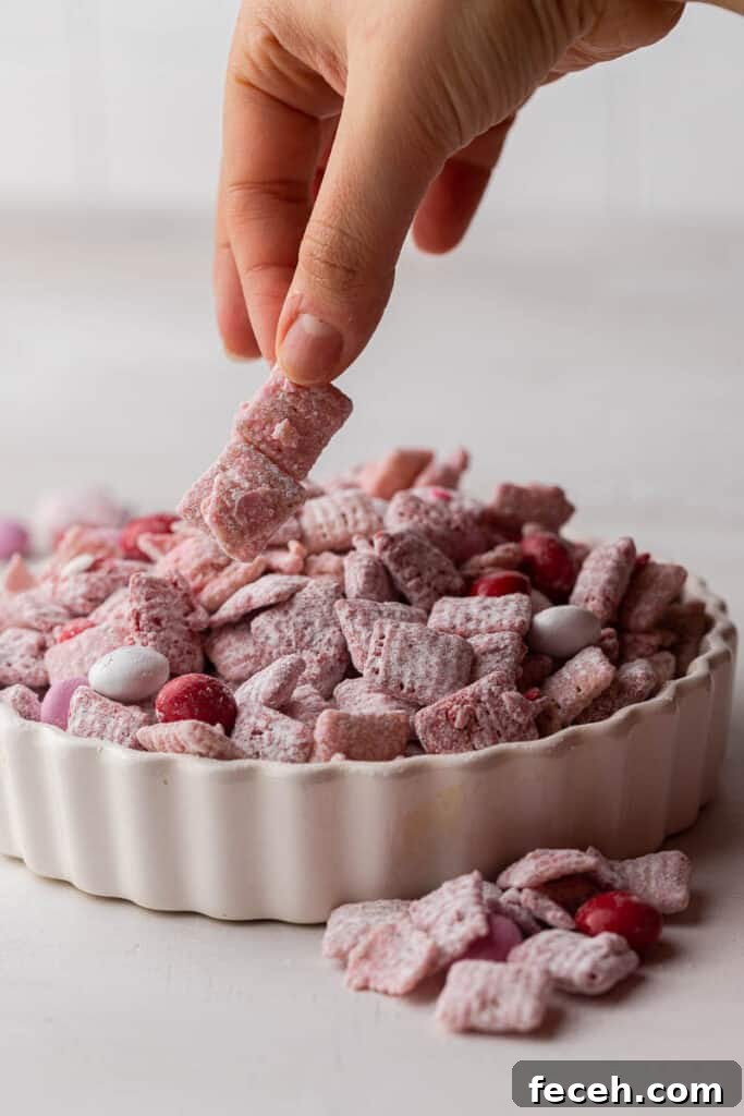 Hand grabbing Valentine’s Day muddy buddies from a bowl
