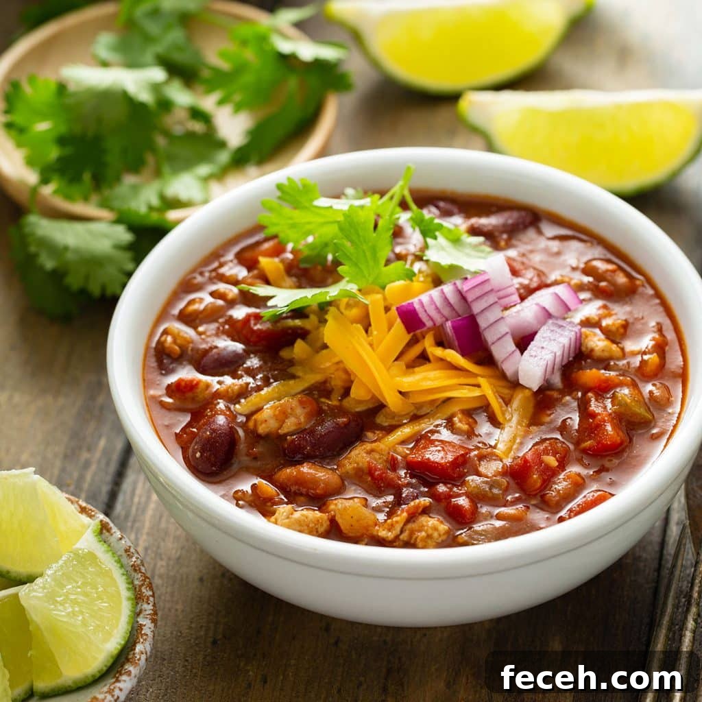 Cook Once, Eat Twice: Budget Meals That Become Delicious Leftovers 13 Turkey chili in a white bowl garnished with chopped red onion, shredded cheese and cilantro