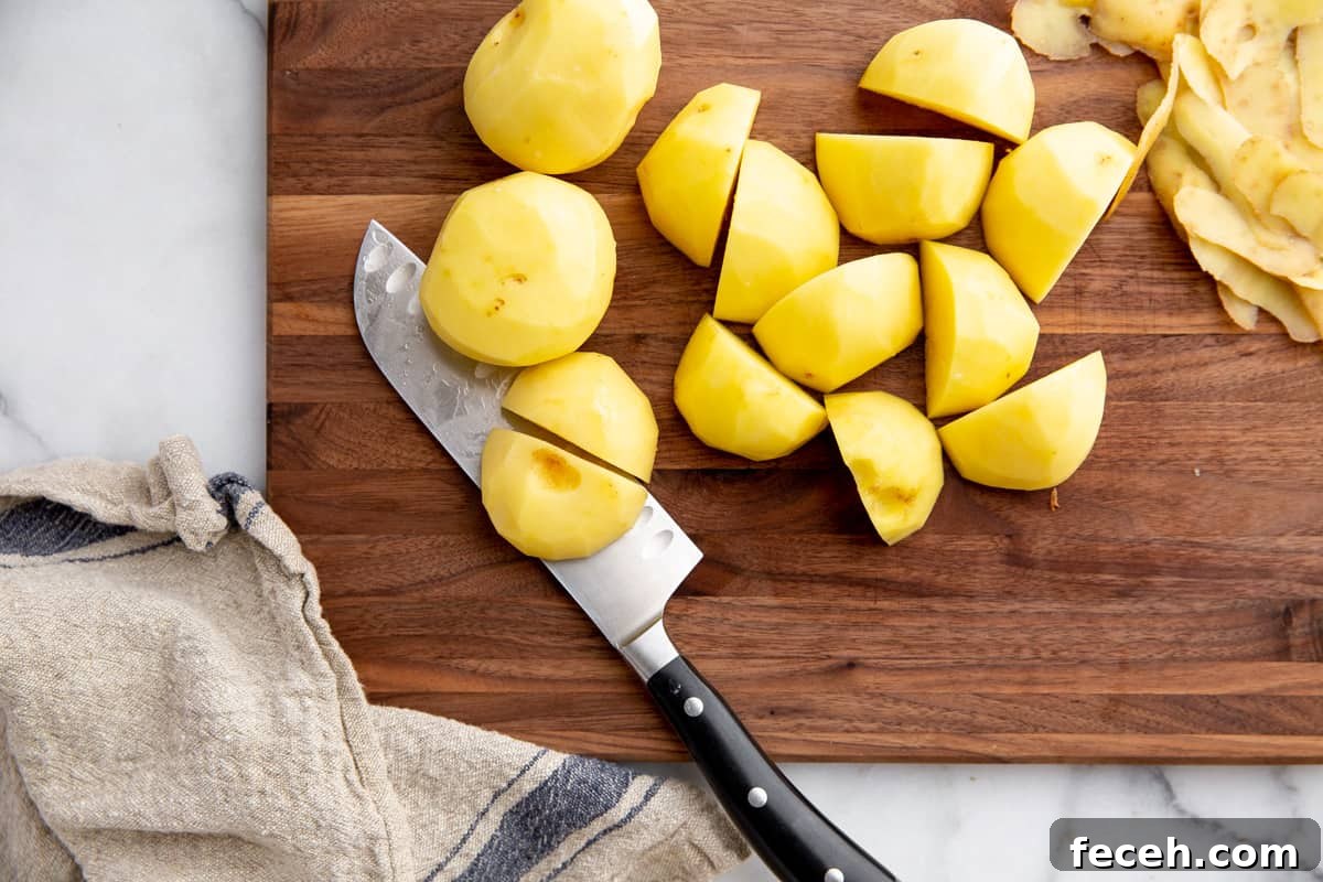 Peeled Yukon gold potatoes cut into chunks on a cutting board. 