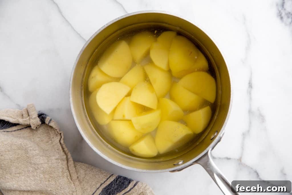 Process shot showing potatoes in a pot with water for the pomme puree recipe.